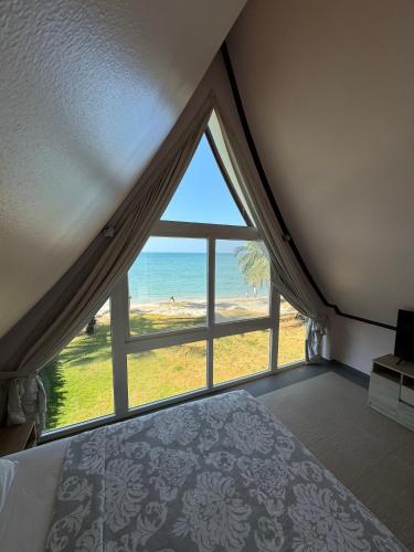 a bedroom with a large window with a view of the beach at Rosdao Beachfront Villa in Ban Khlong Son