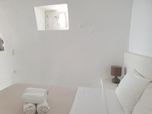 a white bedroom with two towels on a bed at Kalypso Tholos in Astypalaia