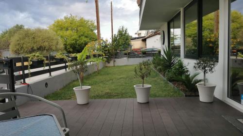 three potted trees in white pots on a porch at Villa Olympia in Paralia Katerinis