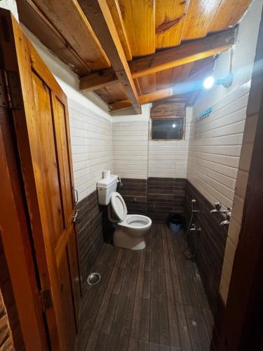 a bathroom with a toilet and a wooden floor at Peaceful Mountain Cottage in Bhīm Tāl