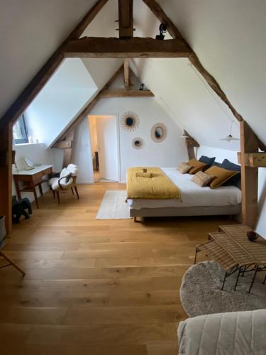 a attic bedroom with a bed and a desk at Le Logis de la Lettre in Tinténiac