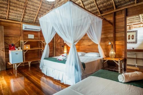 two beds in a room with a canopy at Pousada BGK in Barra Grande