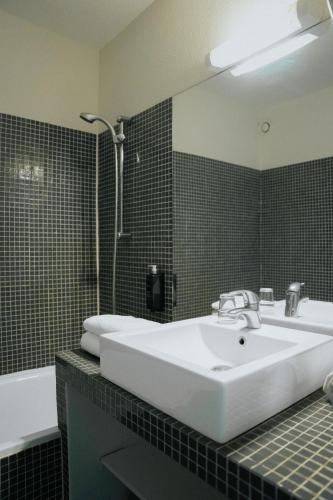 a bathroom with a white sink and a bath tub at Hôtel d'Orsay Grand Matabiau in Toulouse