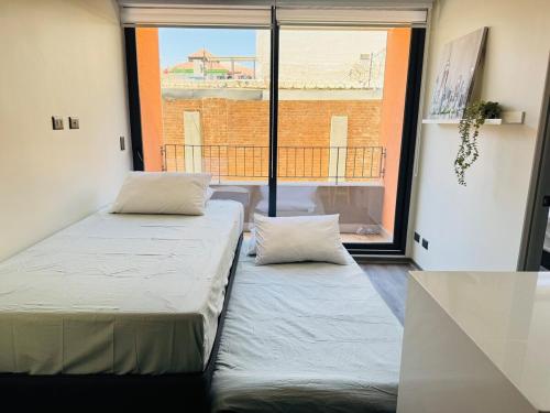two beds in a room with a large window at Muelle Barón - Terminal de Buses in Valparaíso