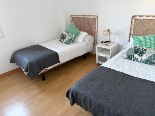 a bedroom with two beds and a lamp on a wooden floor at Casa Rebeca in Torre de Benagalbón