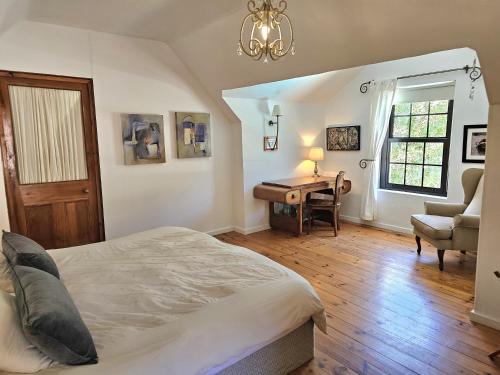 a bedroom with a bed and a desk and a chair at The Gables in Hout Bay
