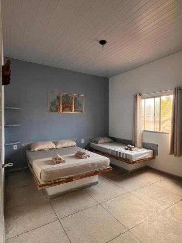 a room with two beds in it with a window at La Palma Hostel & Bar in Maragogi