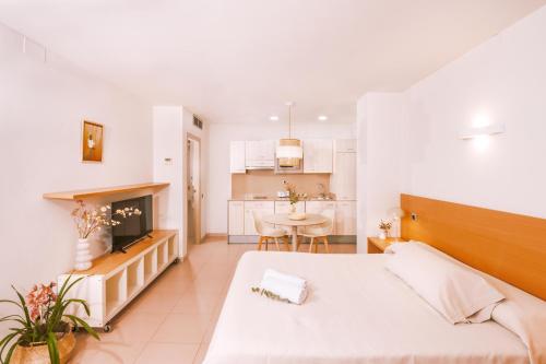 a bedroom with a bed and a kitchen with a table at Apartamentos Porta Coeli in Castelldefels