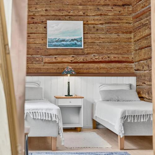 two beds in a room with a wooden wall at Wiedemanni Apartments in Haapsalu