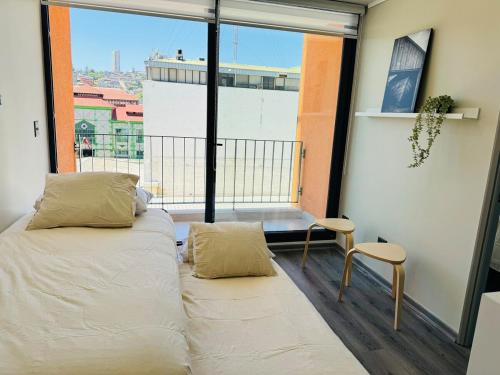 a bedroom with a bed and a large window at Terminal de Buses - Centro de Valparaíso in Valparaíso