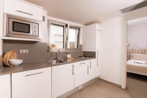 a white kitchen with a sink and a microwave at Apartamentos Castellmar in Castelldefels