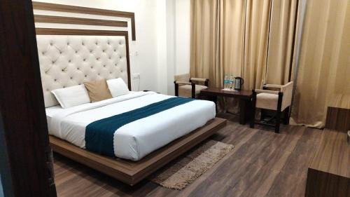 a bedroom with a large bed and a table and chair at As Residency in Dehradun