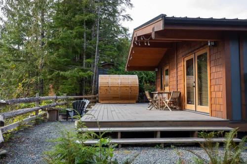 a cabin with a deck and chairs on it at Explorer's Retreat Sauna & Bunkhouse & Fire pit in Port Renfrew