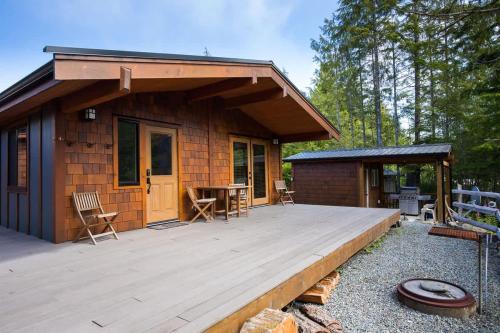 a cabin with a wooden deck in front of it at Explorer's Retreat Sauna & Bunkhouse & Fire pit in Port Renfrew
