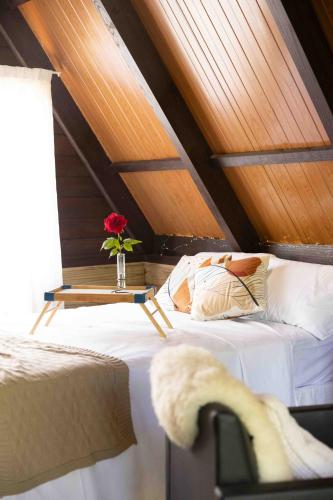 a bedroom with a bed and a table with a flower on it at Recanto do Rio Chalé na Natureza in Rio dos Cedros