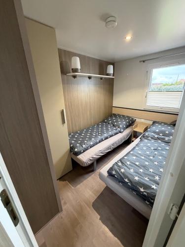 two beds in a small room with a window at Seacottage Blankenberge-Wenduine in De Haan