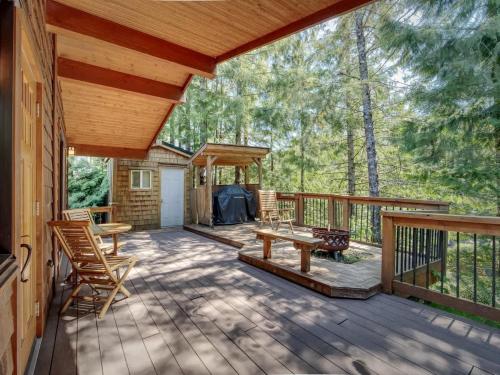 a porch of a cabin with a table and chairs at Hot Tub - Large Fully Enclosed deck - Pet Friendly in Port Renfrew