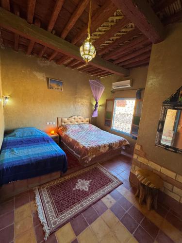 a bedroom with two beds and a chandelier at GITE LA GROTTE VALLEE in Aoûtouss
