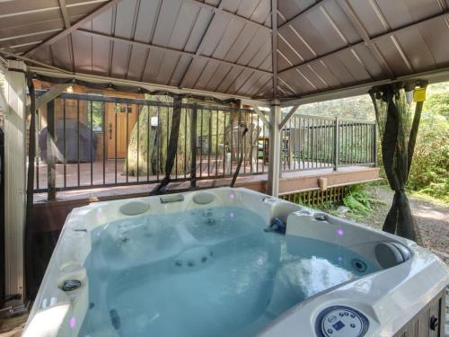 a jacuzzi tub under a roof with a deck at Hot tub Oasis Among Trees - Pet Friendly in Port Renfrew