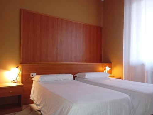 two beds in a hotel room with white sheets at Il Leone D'Oro in Telgate