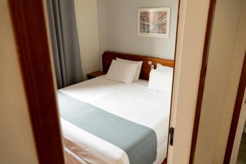 a small bedroom with a bed with white sheets at New Life Piracicaba by Atlantica in Piracicaba