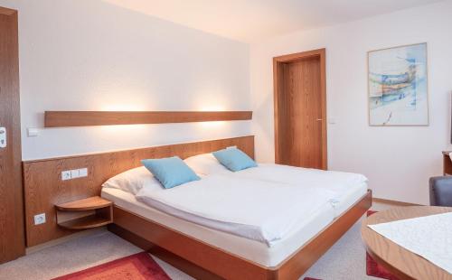 a small bedroom with a bed with white sheets and blue pillows at Hotel Gästehaus Hirsch in Remseck-Pattonville