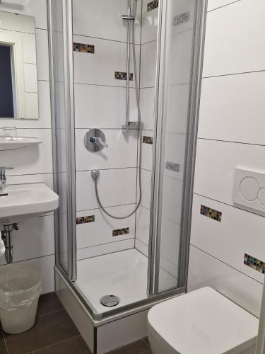 a bathroom with a shower with a toilet and a sink at Hotel Gästehaus Hirsch in Remseck-Pattonville
