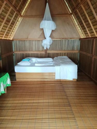 a bedroom with a bed in a wooden room at Or Mandira Homestay in Pulau Penemu