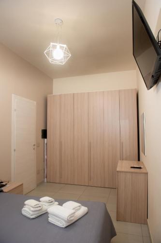 a bedroom with a bed and a tv and towels at ASARO Camere in Campobello di Licata