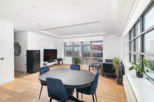 a living room with a table and blue chairs at Cozy and Spacious Central London room in Canary Wharf with a City View & a Private Bathroom in London