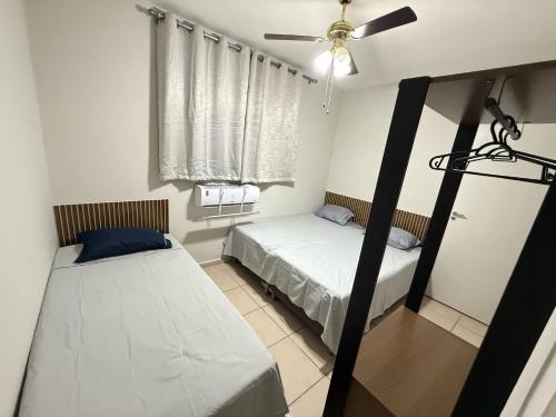 a bedroom with two beds and a ceiling fan at Apartamento próximo Santa Casa e ABQM in Araçatuba