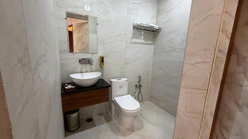 a bathroom with a white toilet and a sink at Hotel Advika in Kaithal
