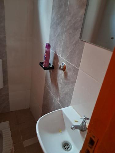 a bathroom with a sink and a pink candle on a shelf at Watene's Homes in Nairobi