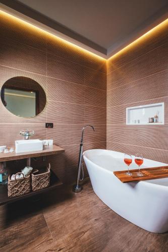 a bathroom with a tub and two glasses of wine at Paineira Vila Flat in Paraisópolis