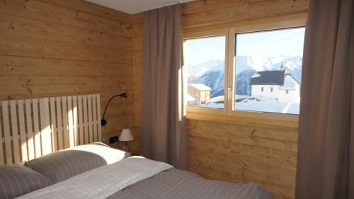 a bedroom with a bed and a large window at Chalet Sofia in Bettmeralp