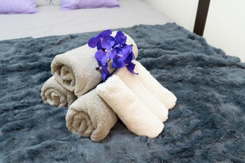 a towel stuffed animal with a purple flower on a bed at JPtrad 葵 なんばや心斎橋にも直結の8名様まで宿泊可能の広々メゾネット in Osaka