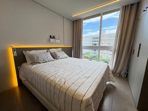 a bedroom with a large bed with a large window at Loft Livin em Atlântida ao lado do Ramblas in Xangri-lá