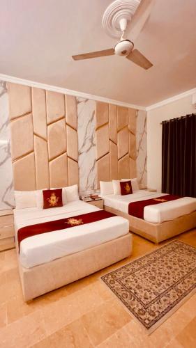a bedroom with two beds and a ceiling fan at Hazelton in Islamabad