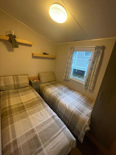 two beds in a small room with a window at 26 The Green Captains Cabin in Crantock