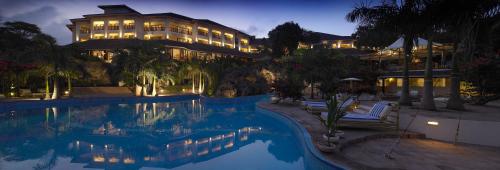 un hotel con piscina frente a un edificio en Diani Reef Beach Resort & Spa, en Diani Beach