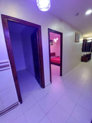 a room with two doors and a room with a red bed at إقامة المول in Fort de lʼEau