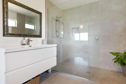 a white bathroom with a sink and a mirror at Whangaroa Casa Roca House in Kaeo