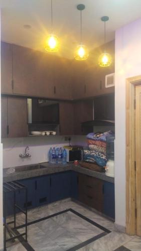 a kitchen with blue cabinets and lights on the ceiling at The 104-H in Faisalabad