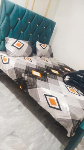 a bed with a blue headboard and pillows on it at The 104-H in Faisalabad