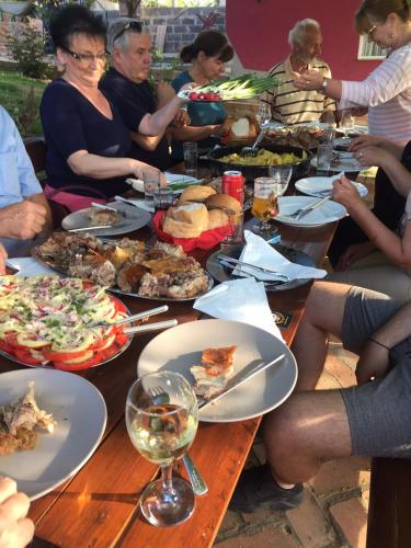 a group of people sitting around a wooden table with food at Ranč Petar Alavanja Banstol in Sremski Karlovci