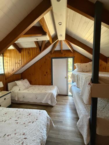 a attic room with three beds in it at Hotel y Cabañas Molino Viejo in Puerto Varas