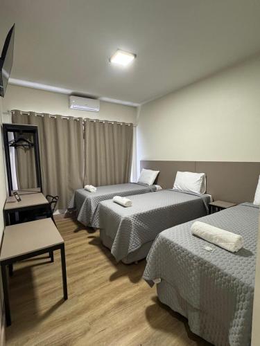 a hotel room with two beds and a chair at Him Hotel in Iraí de Minas