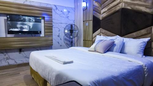 a bedroom with a large bed with a tv on a wall at Royal Modak Resort & Hotel in Ibadan