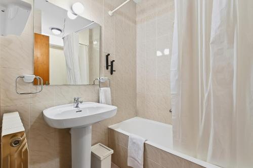 a white bathroom with a sink and a shower at Hotel Xalet Besolí in Arinsal