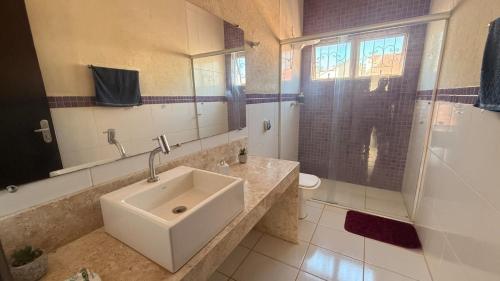 a bathroom with a sink and a toilet and a mirror at Casa Shanti - conforto e tranquilidade. in Dourados